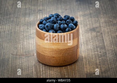 Freshly picked blueberries in wooden bowl on wooden background. Healthy eating and nutrition. Stock Photo