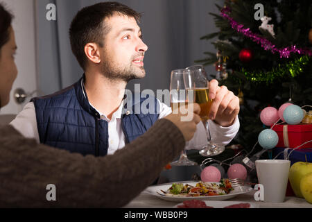Family couple having christmas dinner with champagne and watching tv Stock Photo
