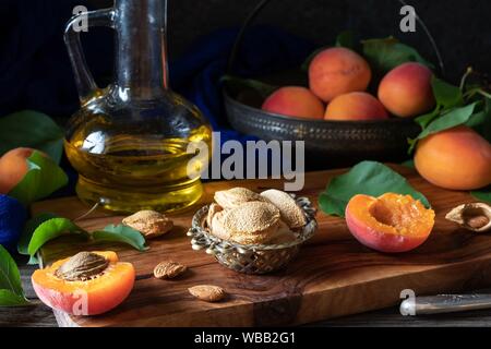 Apricot kernels, with fruit and oil in the background.