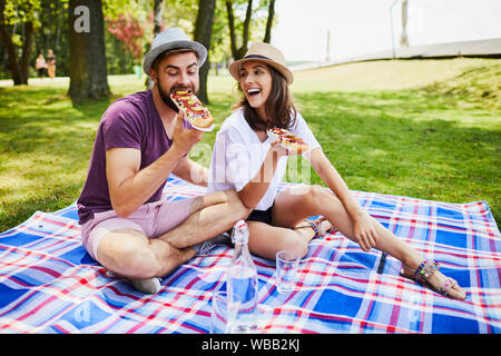 Young couple having picnic in park together and eating Stock Photo