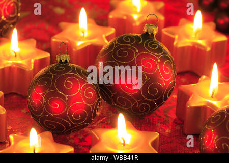 Red Christmas baubles and burning small, star shaped candles. Studio picture. Switzerland Stock Photo
