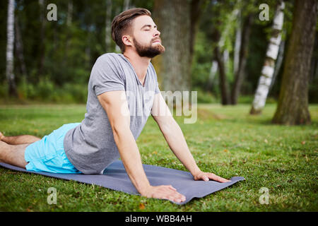 Young man doing yoga outdoors in the morning during summer Stock Photo