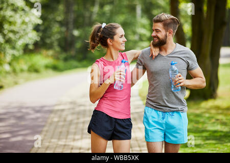 Young couple taking break while joging and embracing in the park Stock Photo