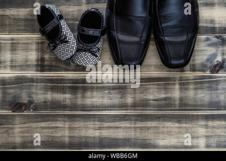 daddy's black business shoes and black and white kids sneakers side by side on grunge rusty wood, concept of family, single parent and father's day, T