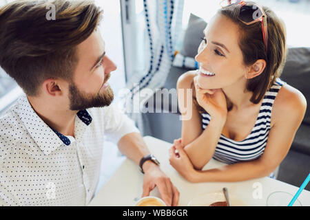 Top view of young couple talking and laughing while sitting in cafeteria relaxing and drinking coffee Stock Photo