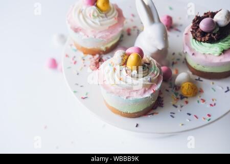 Selective closeup shot of Easter bunny and cupcakes on a white ceramic cake stand Stock Photo