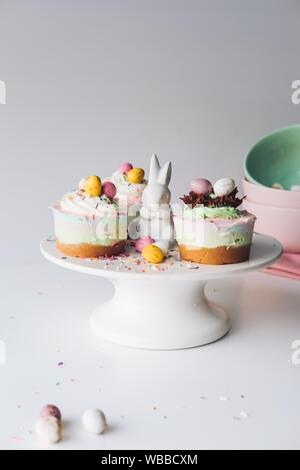 Vertical shot of Easter bunny and cupcakes on a white ceramic cake stand Stock Photo