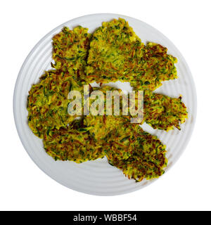 Zucchini pancakes with white sauce on withe plate. Isolated over white background Stock Photo