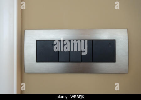 Five-way switch with black buttons and an aluminum frame on a green wall background Stock Photo