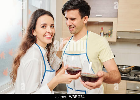 Smiling young man looking at his girlfriend and toasting with glass of red wine Stock Photo
