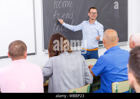 Adult lecturer talking to mixed age  students during seminar Stock Photo
