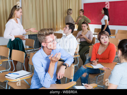 Happy group of adult students lively chatting while enjoying free time in class Stock Photo