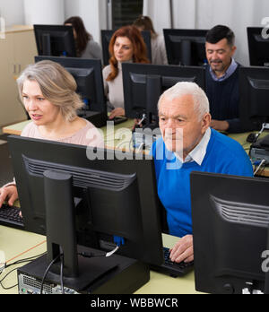 Computer lessons for adults. Group of people of different ages learning to use computers in classroom Stock Photo