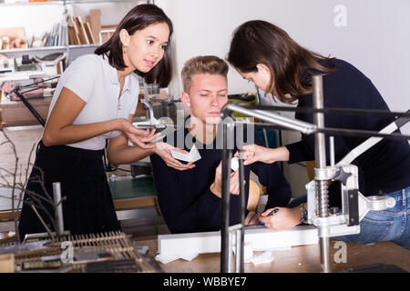 Students and teacher of architecture faculty discussing details of architectural model in university workshop Stock Photo
