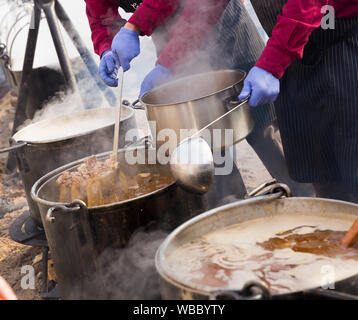 Traditional cooking in iron cauldrons hanging over open fire on medieval city festival Stock Photo