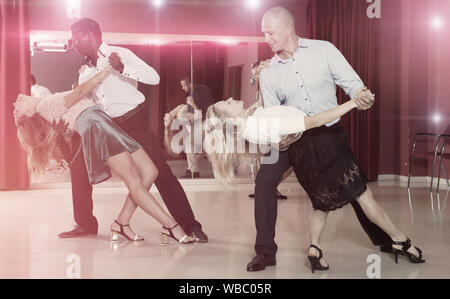Young smiling people practicing passionate samba in dance class Stock Photo