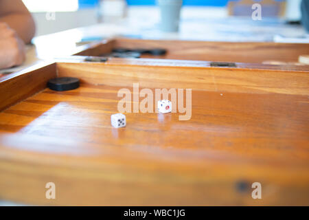 Playing backgammon on a wooden table with dices. Stock Photo
