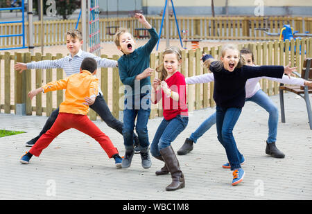 happy european children showing different figures during game in playground outdoors Stock Photo