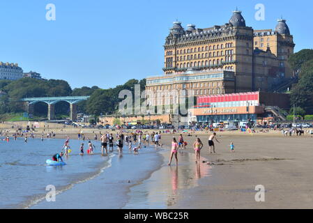 The Grand Hotel, Scarborough, North Yorkshire, UK, 26th August 2019, Weather: Families on the beach. Hot and sunny August bank holiday Monday morning and temperature records are expected to be broken across eastern England for the late summer holiday. People flock to the seafront and beach in this traditional English seaside town on the north east coast. Stock Photo