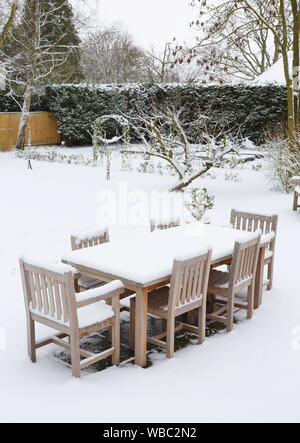 Snow covered English garden and patio furniture, UK Stock Photo