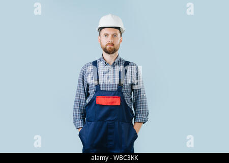 Confident construction worker in a white helmet and blue overalls Stock Photo