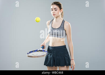 A woman tennis player bouncing the ball on the racket, isolated on a white background. Stock Photo
