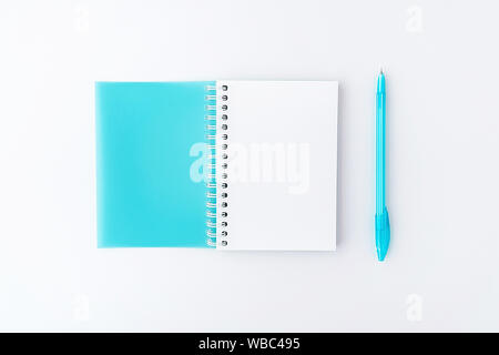 Top view of opened light blue cover spiral notepad with pen on white desk background. Mockup for your design. Flat lay. Stock Photo