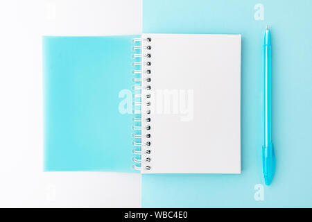 Top view of opened light blue cover spiral notepad with pen on blue and white background. Mockup for your design. Flat lay. Stock Photo
