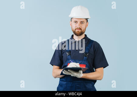 Construction engineer in a white helmet and blue uniform writing notes Stock Photo