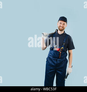 Portrait of a smiling service worker holding tools, dressed in uniform Stock Photo