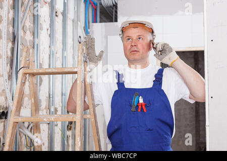 Construction worker having serious phone conversation at indoors building site Stock Photo