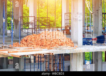 Red bricks pile interior room building construction and cement wall background Stock Photo