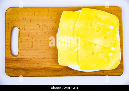 Sliced hard cheese on a wooden cutting board. Food. Stock Photo