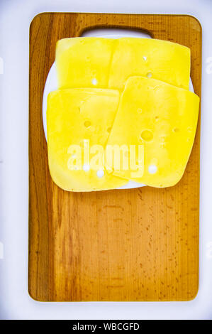 Sliced hard cheese on a wooden cutting board. Food. Stock Photo