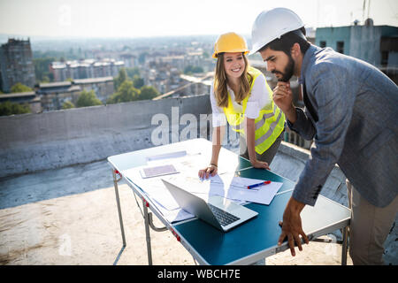 Architects team and engineers looking paper plans at construction site. Stock Photo