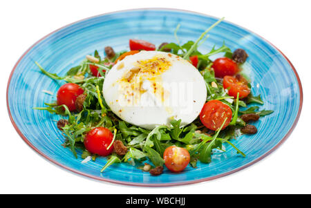 Salad with fresh burrata cheese with arugula, tomatoes, raisins and pine nuts. Isolated over white background Stock Photo