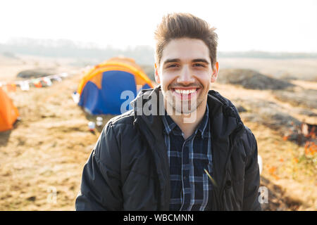 Handsome cheerful man camping outdoors Stock Photo