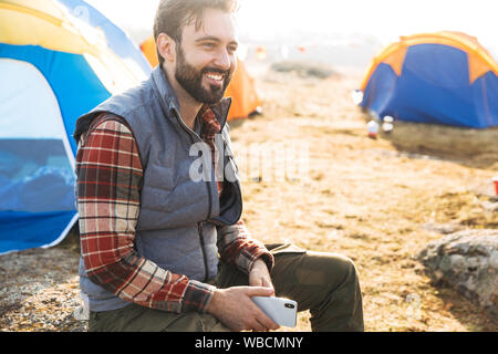 Handsome cheerful bearded man camping outdoors Stock Photo