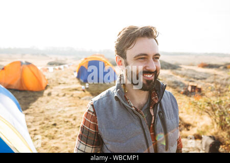 Handsome cheerful bearded man camping outdoors Stock Photo