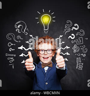 Happy smart child boy in blue suit and  lightbulb Stock Photo