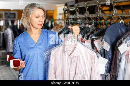 Portrait of diligent  cheerful smiling female laundry worker at her workplace Stock Photo