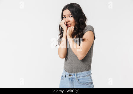 Image of shocked brunette woman 20s dressed in basic clothes grabbing her face in fright isolated over white background Stock Photo