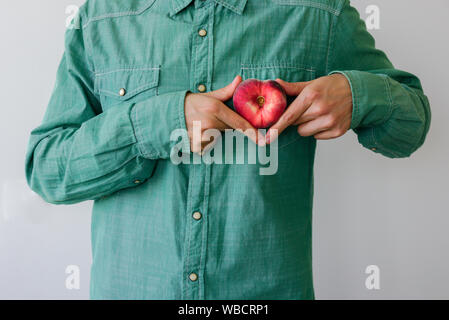 Man in green shirt with heart shaped peach in his hands Stock Photo