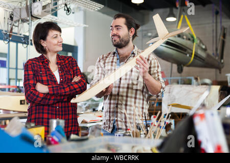 Team of happy aircraft enthusiasts working in workshop on creating of airplane models Stock Photo