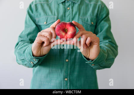 Man in green shirt with heart shaped peach in his hands Stock Photo