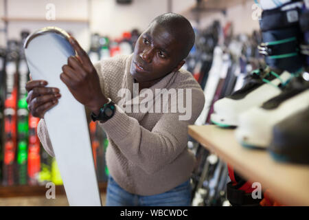 Young African American looking for new skis at a ski equipment shop Stock Photo