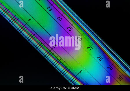 Cross polarised image of a ruler showing the colourful stress patterns in the plastic Stock Photo