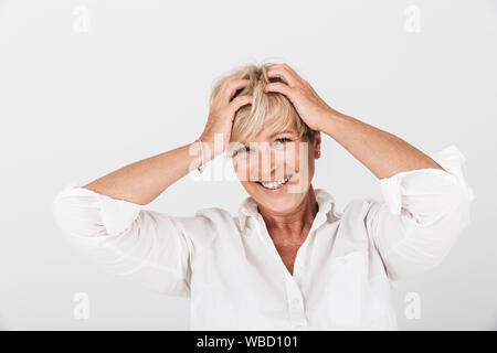 Portrait of delighted adult woman with short blond hair grabbing her head and laughing at camera isolated over white background in studio Stock Photo