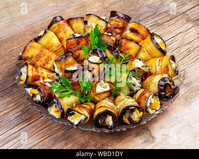 rolls of fried eggplant stuffed with tomatoes, mayonnaise and garlic on a wooden background close-up Stock Photo