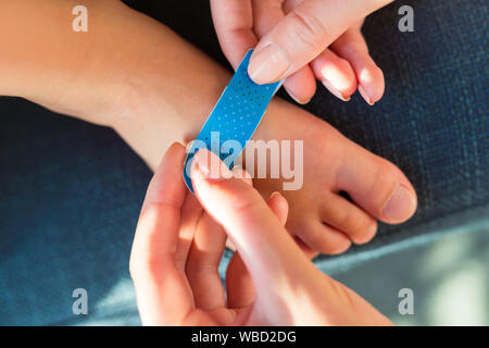 Woman applying sticking plaster to little child foot close up view Stock Photo